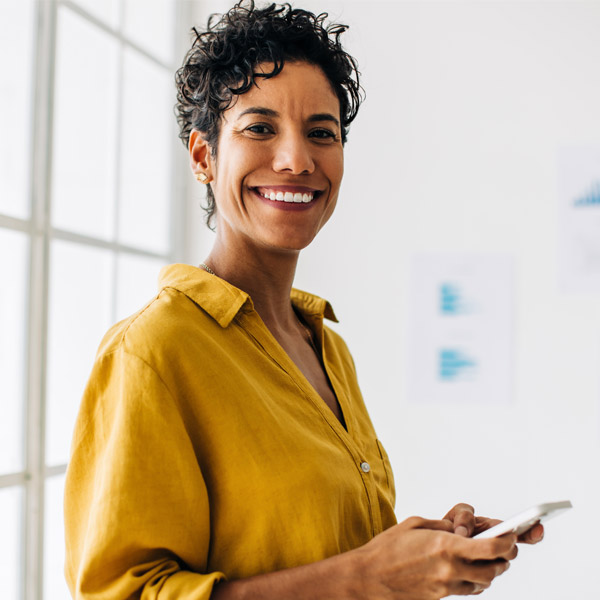 woman smiling while holding cellphone